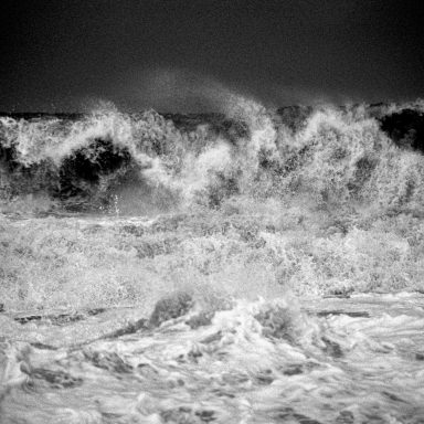 Vagues puissantes éclaboussant dans un océan agité en noir et blanc.