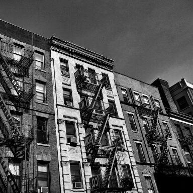 Bâtiment urbain en noir et blanc avec balcons et escaliers de secours.