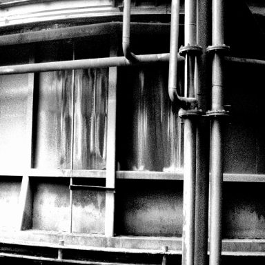 Pipes en métal noir et blanc sur une surface industrielle texturée.