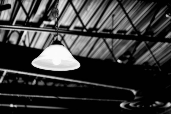 Ampoule suspendue sous un plafond industriel en métal.
