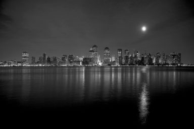 # Lune,8 Vue nocturne en noir et blanc d'une ville avec un ciel étoilé et le reflet sur l'eau.