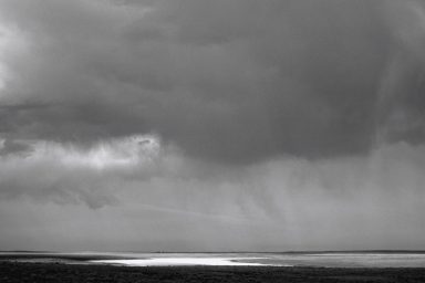 # Sombre Ciel nuageux avec des reflets sur une étendue d'eau sombre.